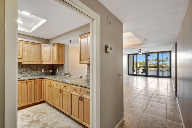 kitchen with light stone counters, a wall of windows, decorative backsplash, and light brown cabinets