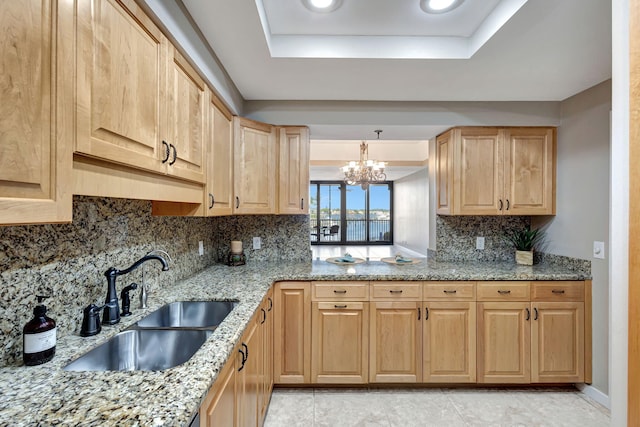11370 Twelve Oaks Way Unit 217, North Palm Beach, FL 33408 - kitchen with a tray ceiling, a sink, a chandelier, backsplash, and light brown cabinetry