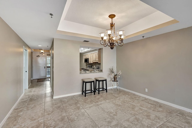 dining room with a tray ceiling, a chandelier, and light tile patterned floors