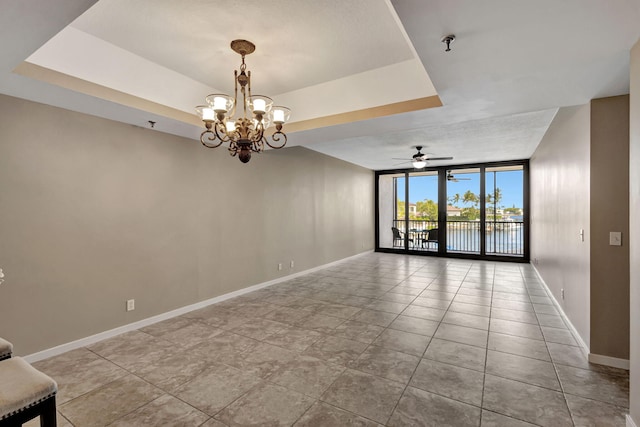 unfurnished room featuring light tile patterned floors, ceiling fan with notable chandelier, a wall of windows, and a tray ceiling