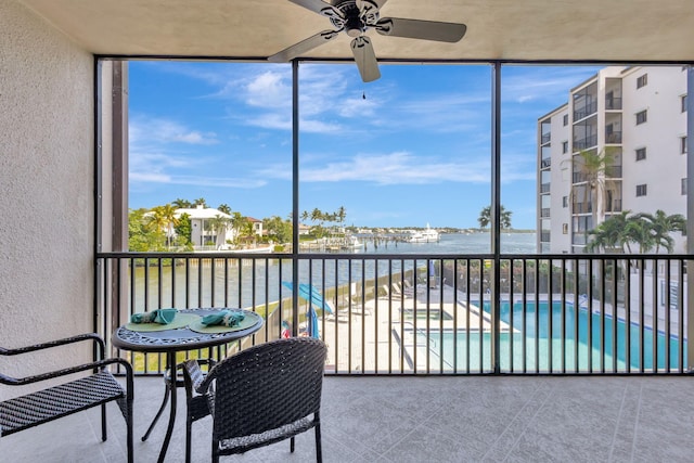 sunroom with a water view and ceiling fan