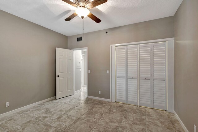 11370 Twelve Oaks Way Unit 217, North Palm Beach, FL 33408 - unfurnished bedroom featuring a closet, baseboards, ceiling fan, and a textured ceiling