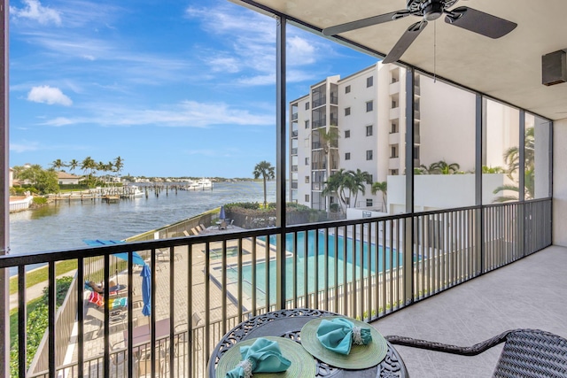 balcony with a water view, a community pool, and ceiling fan