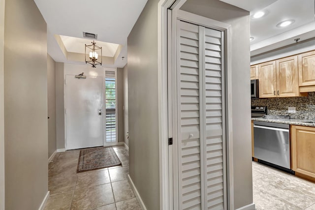 entryway featuring an inviting chandelier and a raised ceiling