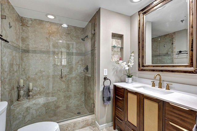 bathroom featuring a shower with door, vanity, and toilet