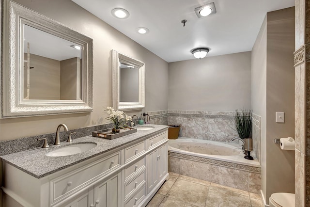 bathroom featuring tiled tub, vanity, and tile patterned floors