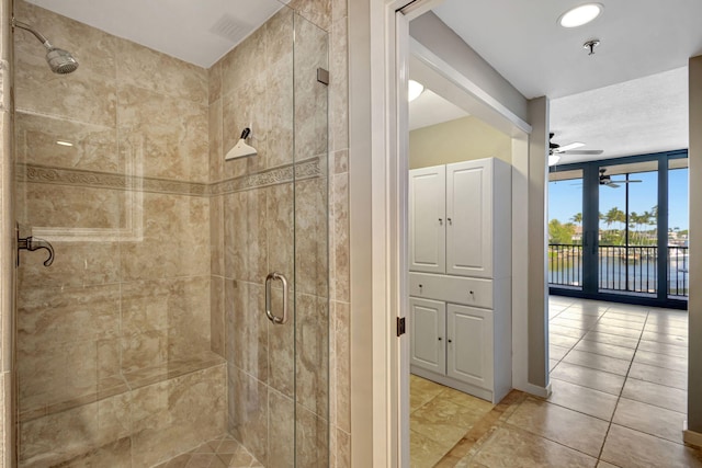 bathroom featuring a water view, tile patterned floors, ceiling fan, and a shower with shower door