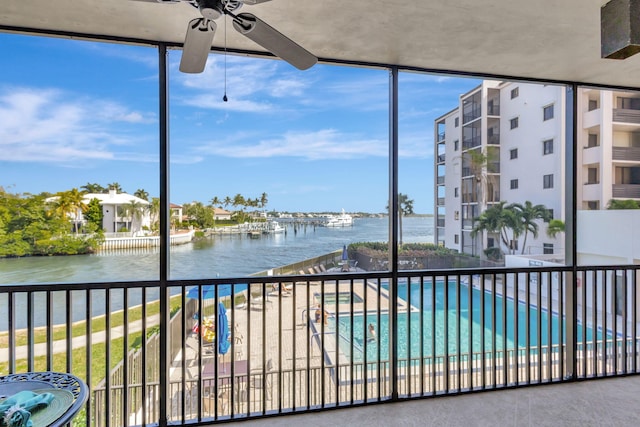 view of swimming pool with ceiling fan and a water view