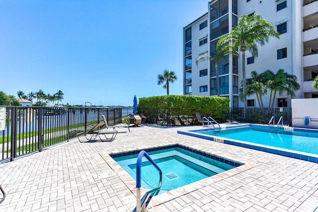 view of swimming pool with a hot tub, a patio, and a water view