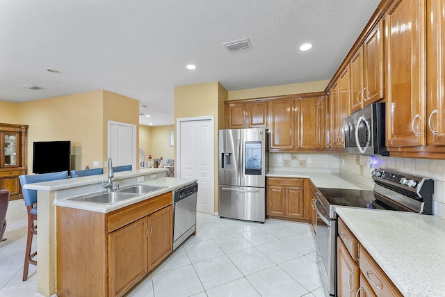 kitchen featuring a breakfast bar, sink, backsplash, light tile patterned floors, and stainless steel appliances