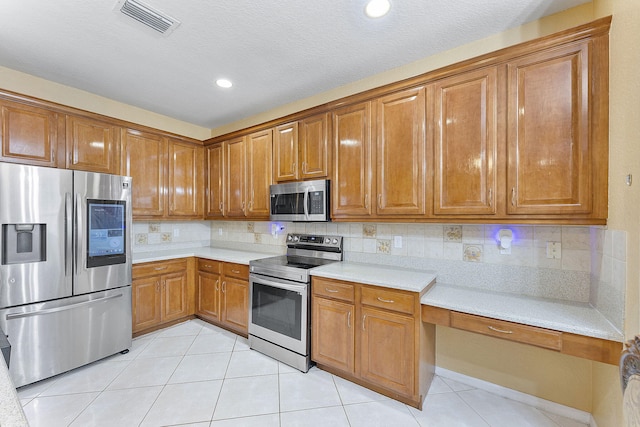 kitchen with stainless steel appliances, light tile patterned floors, and backsplash