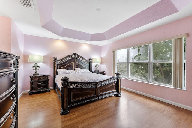 bedroom featuring a tray ceiling and light hardwood / wood-style floors