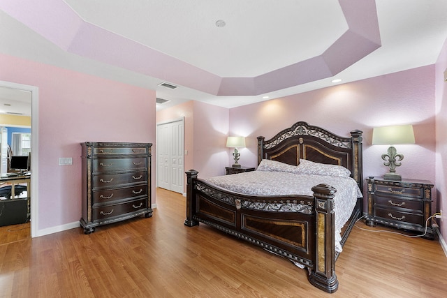 bedroom featuring a raised ceiling, hardwood / wood-style floors, and a closet