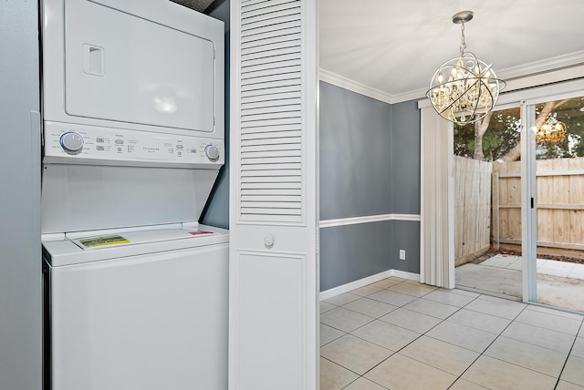 laundry area with ornamental molding, stacked washer and clothes dryer, a chandelier, and light tile patterned flooring