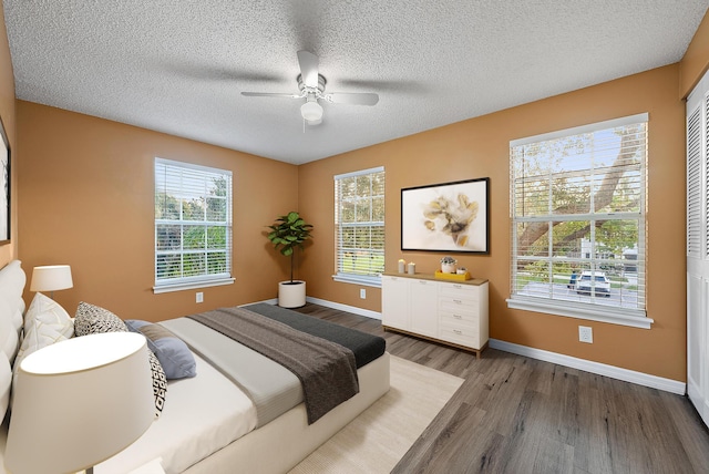 bedroom featuring ceiling fan, hardwood / wood-style floors, and a textured ceiling