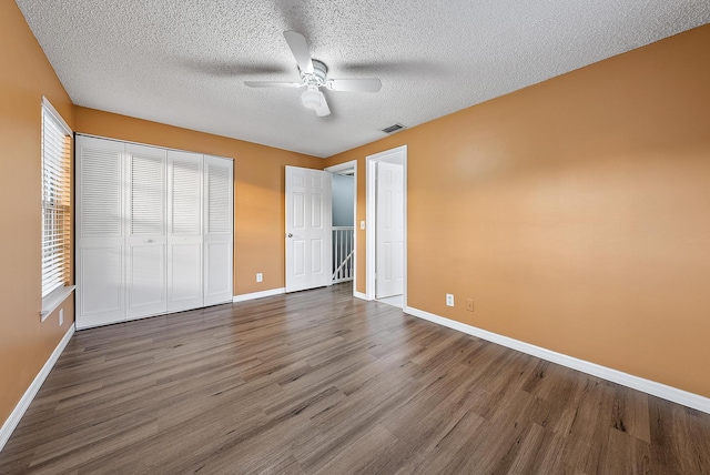 unfurnished bedroom with ceiling fan, dark hardwood / wood-style floors, a textured ceiling, and a closet