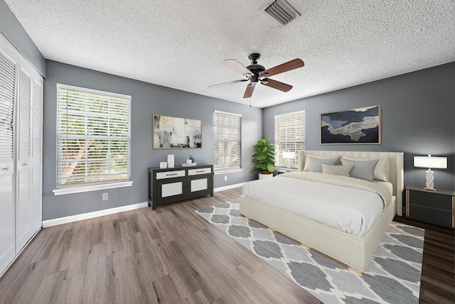 bedroom featuring ceiling fan, a closet, a textured ceiling, and light wood-type flooring