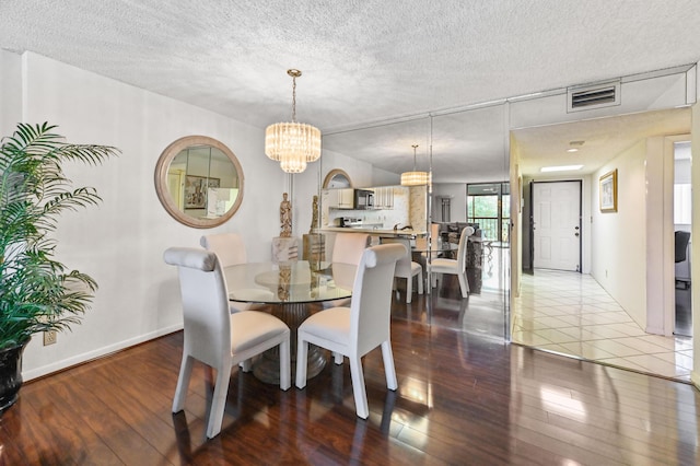 dining area featuring hardwood / wood-style flooring, a notable chandelier, and a textured ceiling