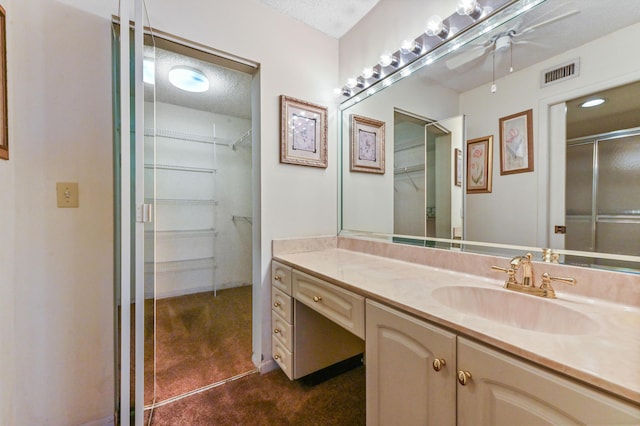 bathroom with vanity, ceiling fan, a textured ceiling, and walk in shower