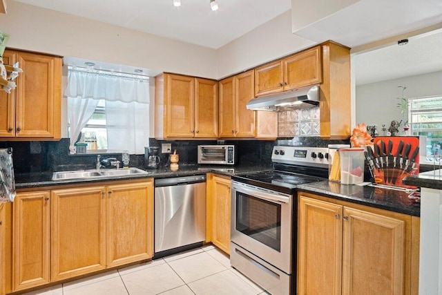 kitchen with sink, appliances with stainless steel finishes, plenty of natural light, tasteful backsplash, and dark stone counters