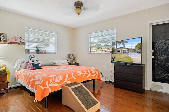 bedroom featuring hardwood / wood-style flooring, ceiling fan, and multiple windows