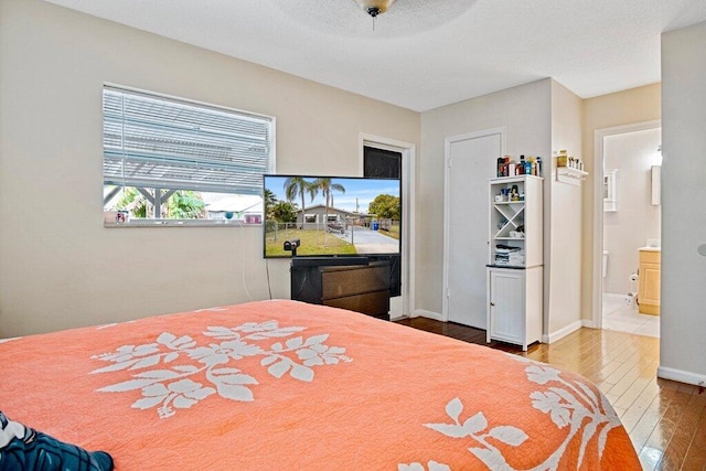 bedroom with ceiling fan, wood-type flooring, and ensuite bath