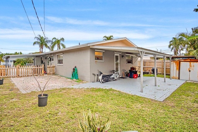 back of house featuring a patio, a lawn, and a storage unit