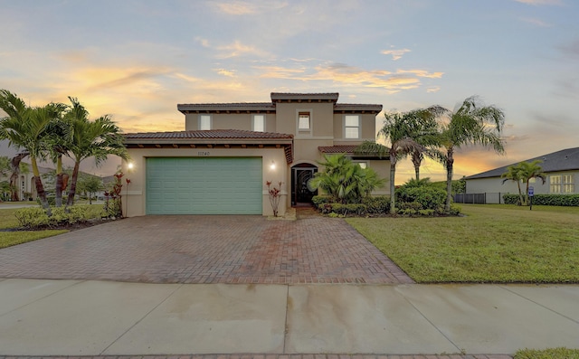 mediterranean / spanish house featuring a garage and a yard