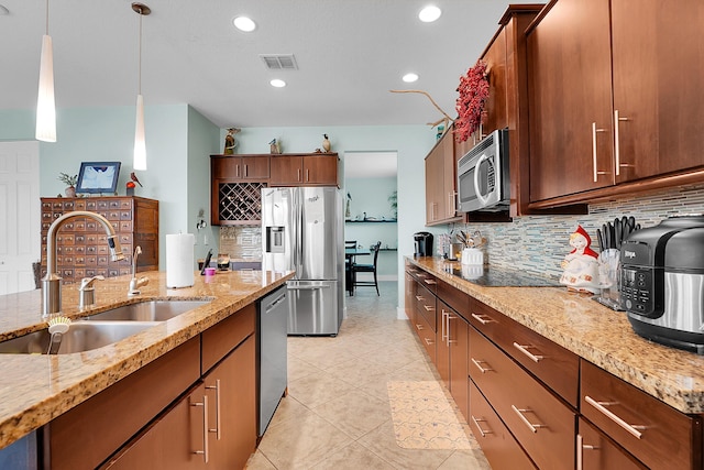 kitchen featuring appliances with stainless steel finishes, pendant lighting, tasteful backsplash, sink, and light stone countertops