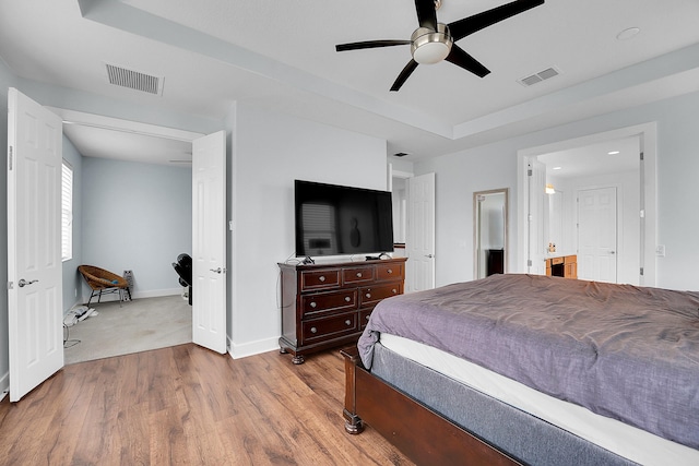 bedroom featuring a tray ceiling, light hardwood / wood-style flooring, and ceiling fan