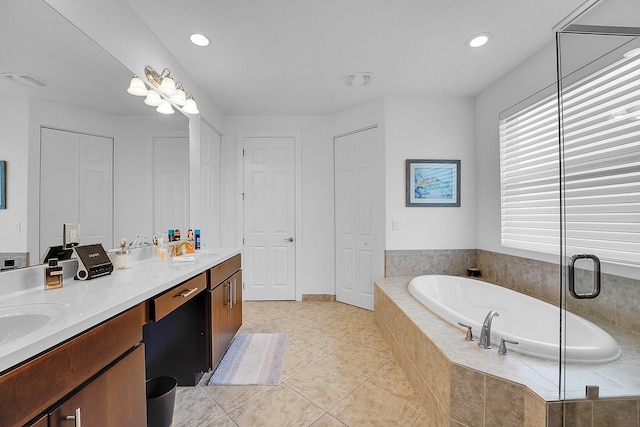 bathroom with tile patterned floors, vanity, and tiled bath