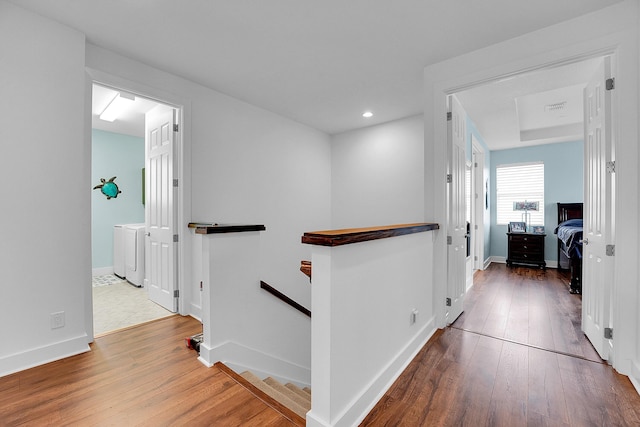 corridor with hardwood / wood-style flooring and washer and dryer