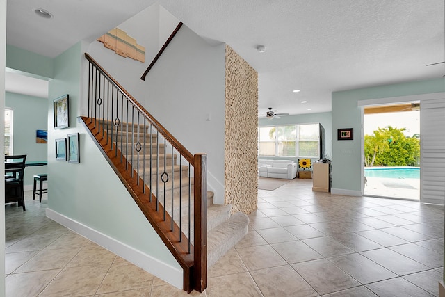 stairway with tile patterned flooring, a textured ceiling, and ceiling fan