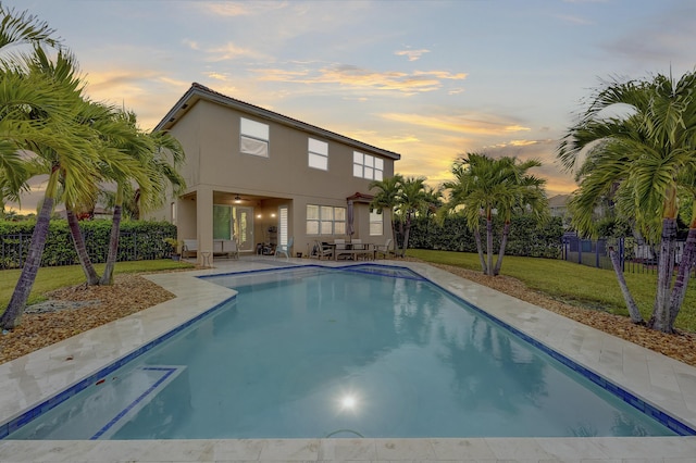 pool at dusk with a yard and a patio area