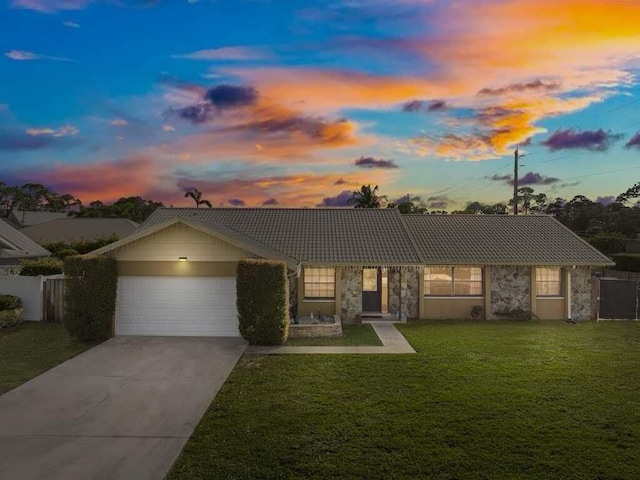 ranch-style home featuring a garage and a lawn