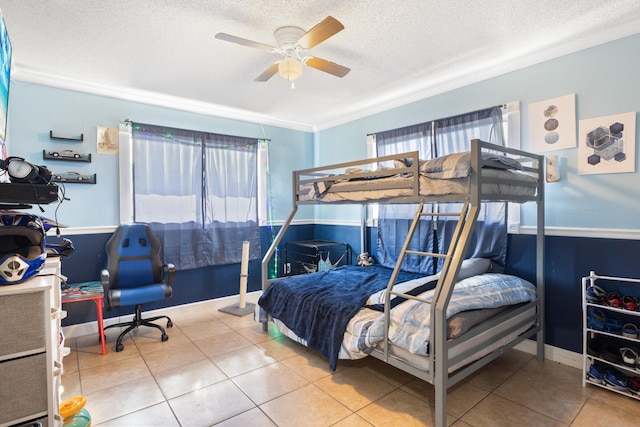 tiled bedroom with a textured ceiling, crown molding, and a ceiling fan