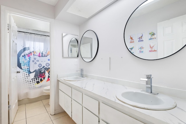 full bath with a sink, toilet, double vanity, and tile patterned flooring