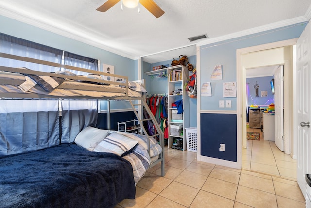 bedroom featuring ornamental molding, ceiling fan, tile patterned floors, and a textured ceiling