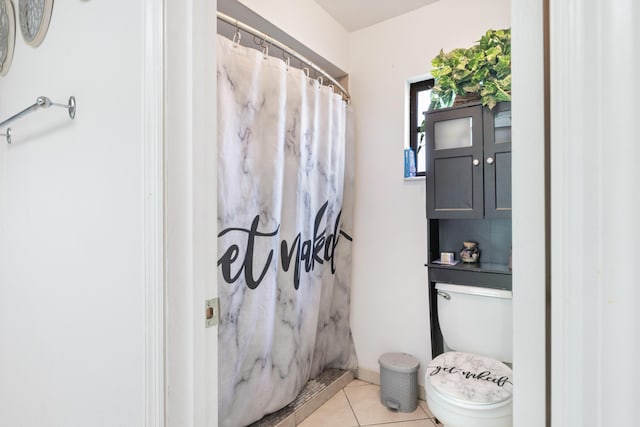 bathroom featuring toilet, curtained shower, and tile patterned flooring