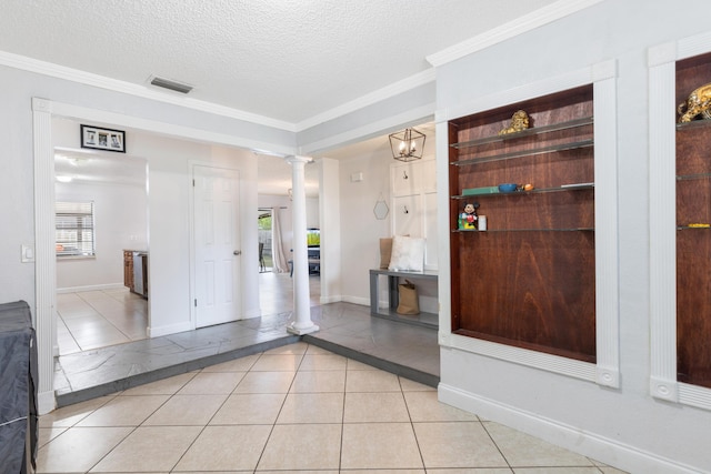 entryway with a wealth of natural light, decorative columns, a textured ceiling, and light tile patterned floors