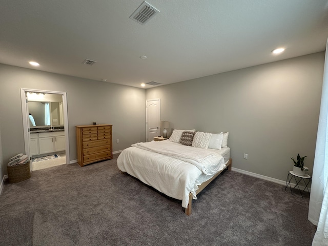 bedroom with dark colored carpet and connected bathroom