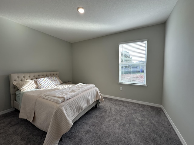 bedroom featuring a textured ceiling and dark colored carpet