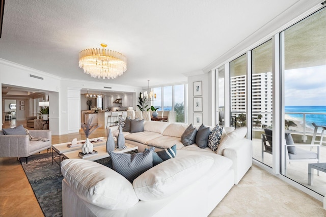 living area with a chandelier, a water view, crown molding, and visible vents