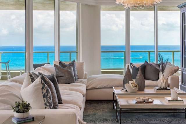 living room with a water view, a chandelier, and a view of the beach