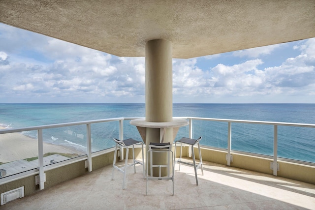 balcony with a water view, a beach view, and visible vents