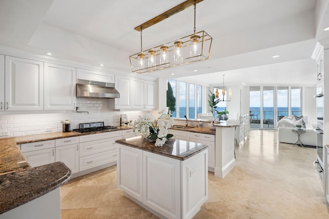 kitchen with pendant lighting, a water view, a kitchen island, and under cabinet range hood