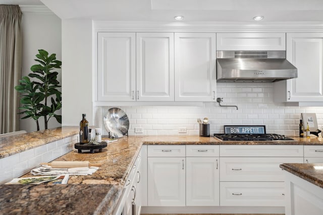 kitchen featuring stone counters, stainless steel gas stovetop, backsplash, white cabinetry, and exhaust hood