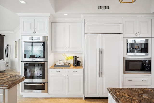 kitchen featuring a warming drawer, visible vents, white cabinetry, built in appliances, and dark stone counters