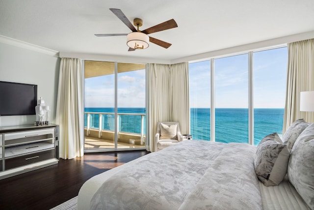 bedroom featuring access to exterior, a water view, multiple windows, and wood finished floors