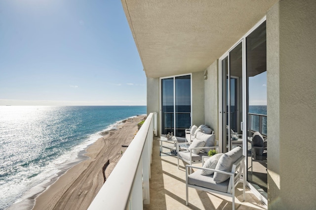 balcony with a water view and a view of the beach